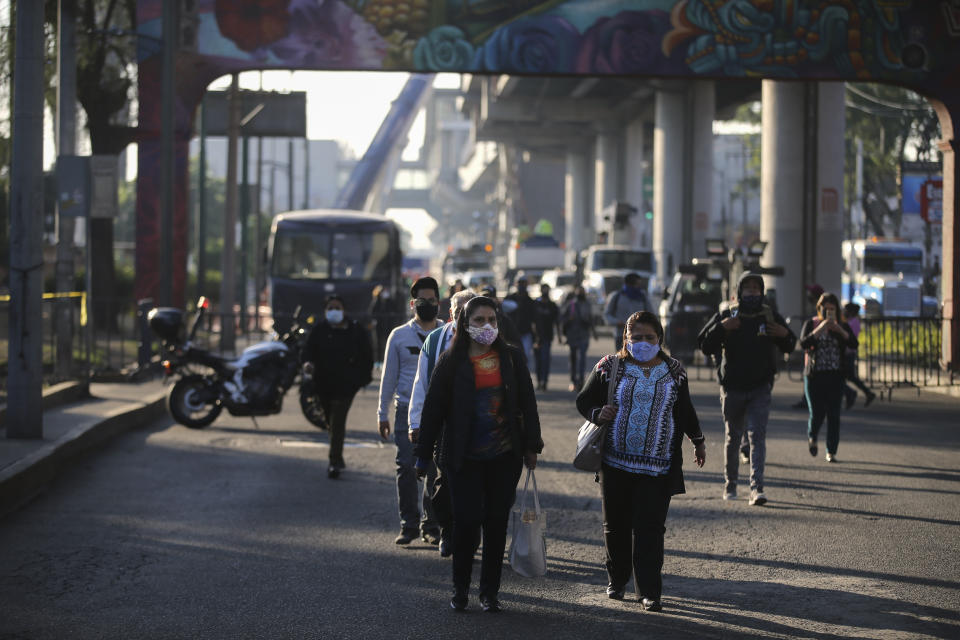 Commuters, looking for an alternate form of transportation, walk near a collapsed elevated section of the subway, in Mexico City, Tuesday, May 4, 2021. The elevated section of the metro collapsed and sent rail cars plunging toward a busy boulevard late Monday, killing at least 23 people and injuring at least 79, city officials said. (AP Photo/Fernando Llano)