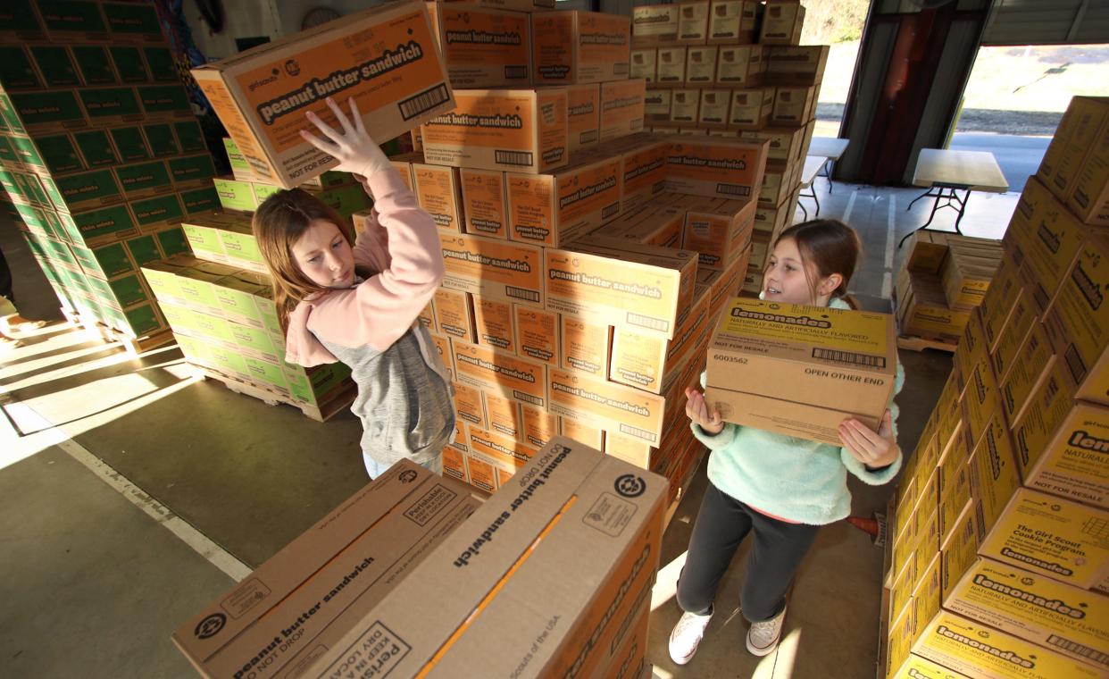 Olivia Brennan and her sister Gracie Brennan pull their cases of Girl Scout cookies for Troop 13294 early Saturday morning, Jan. 13, 2024, at the Gastonia Farmers Market on East Long Avenue.