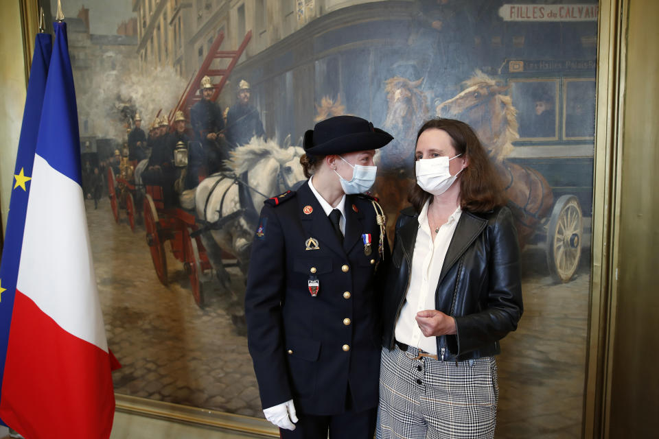 French math teacher-volunteer fighter, Marion Dehecq, left, talks with Paris-based Associated Press journalist Lori Hinnant, after she receives a bronze medal for courage and dedication as she used CPR to save the life of a jogger, during a ceremony with France's minister for citizenship issues, Marlene Schiappa at the Paris fire service headquarters in Paris, France, Monday, May 10, 2021. The jogger's wife, Paris-based Associated Press journalist Lori Hinnant, helped identify the anonymous rescuer by putting up thank-you signs in Monceau Park, where her husband Peter Sigal went into cardiac arrest on April 28. (AP Photo/Francois Mori, pool)