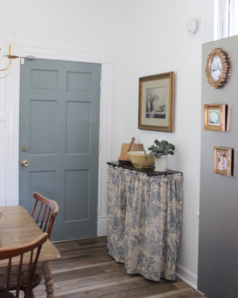 The remodeled kitchen features a refrigerator with fabric-skirted shelves and framed photographs.