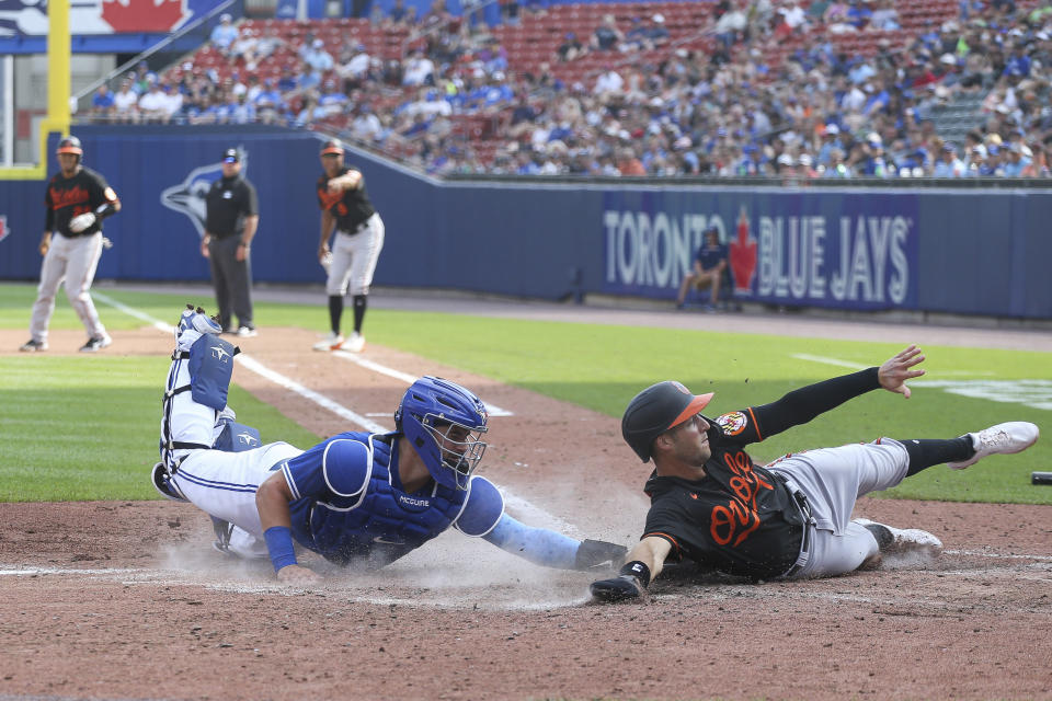 Baltimore Orioles' Stevie Wilkerson (12) evades a tag by Toronto Blue Jays catcher Reese McGuire and slides across home safely on a single by Pedro Severino during the seventh inning of a baseball game in Buffalo, N.Y., Saturday, June 26, 2021. (AP Photo/Joshua Bessex)