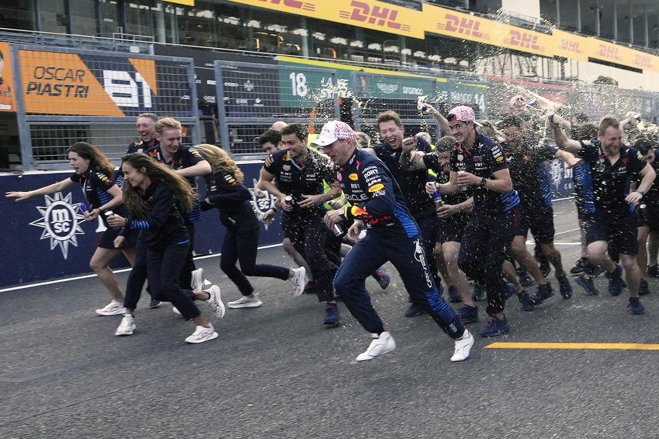 Red Bull team members run to avoid splash of Red Bull drinks after posing for a group photo, following Red Bull drivers Max Verstappen, center, of the Netherlands won the first place in the Japanese Formula One Grand Prix at the Suzuka Circuit in Suzuka, central Japan, Sunday, April 7, 2024. (AP Photo/Hiro Komae)