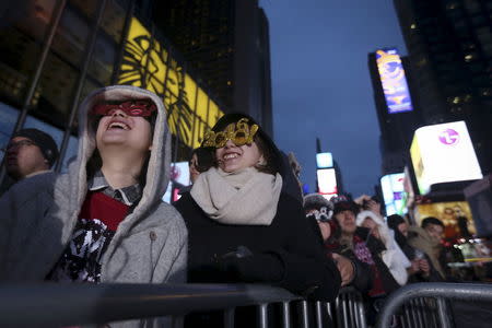 People with 2016 glasses look up as they stand in a penned off area of Times Square during New Year's Eve celebrations in the Manhattan borough of New York, December 31, 2015. REUTERS/Carlo Allegri