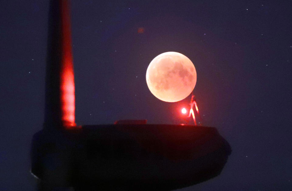 <p>The blades from a wind turbine are silhouetted against the moon in the sky in Novogrudok, Belarus, during a total lunar eclipse on Saturday, July 28, 2018. (Photo: Sergei Grits/AP) </p>