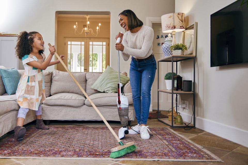 shot of a mother and daughter having fun while cleaning the living room