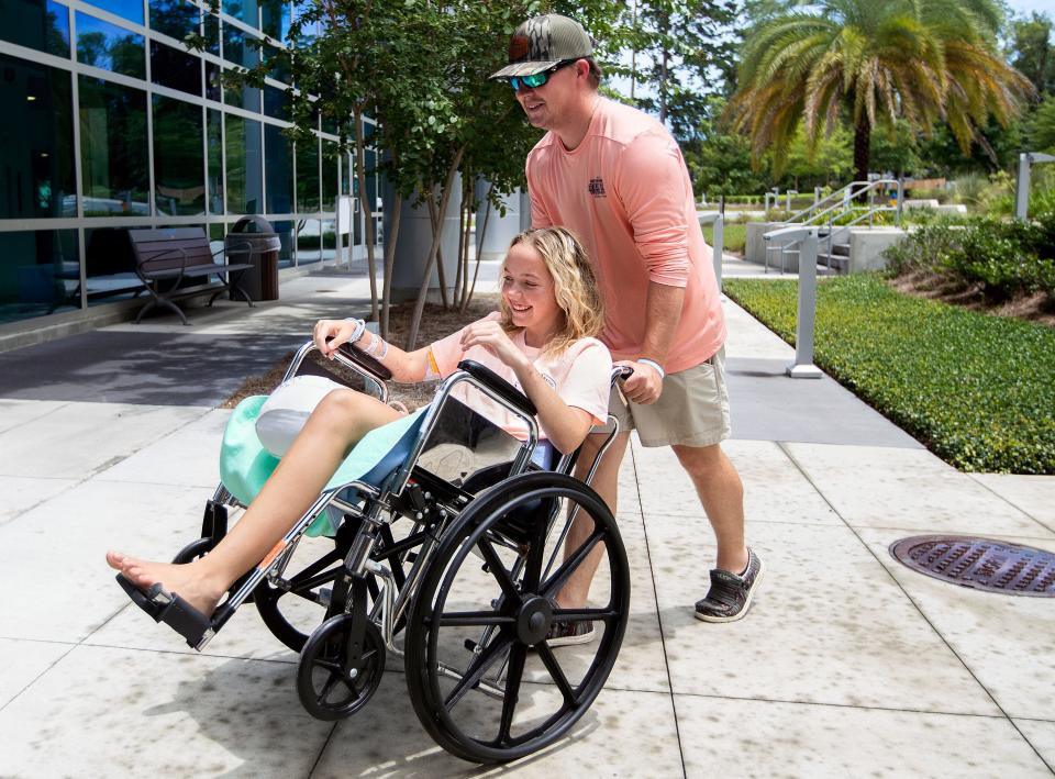 Addison Bethea, whose leg was amputated after a shark attack, is pushed in a wheelchair Wednesday outside Tallahassee Memorial Hospital by her brother, Rhett Willingham.