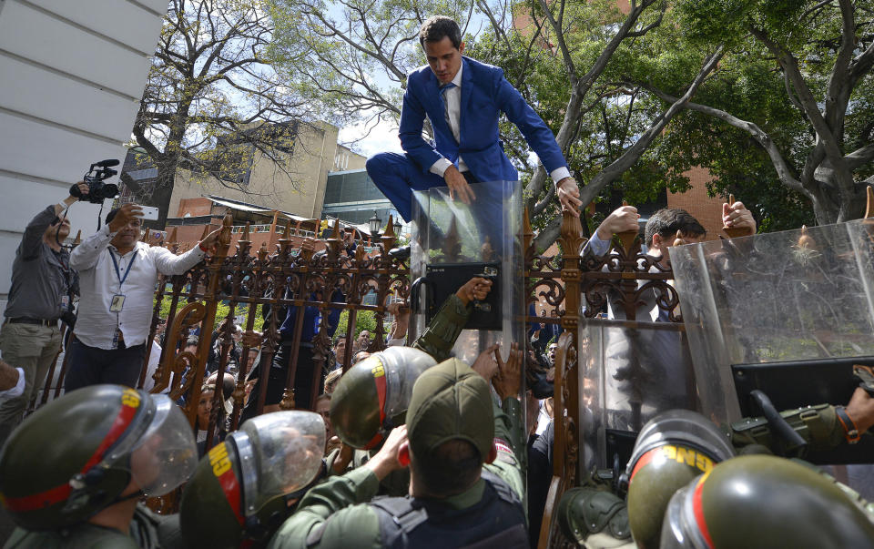 El líder de la oposición y presidente de la Asamblea Nacional de Venezuela, Juan Guaidó, trepa una valla en un intento fallido por ingresar a la Asamblea luego de que fuera nombrada una dirección paralela del Legislativo en Caracas, Venezuela, el domingo 5 de enero de 2020. Con Guaidó atrapado afuera, una lista rival encabezada por el legislador Luis Parra se juramentó como líder de la legislatura. (AP Foto / Matias Delacroix)