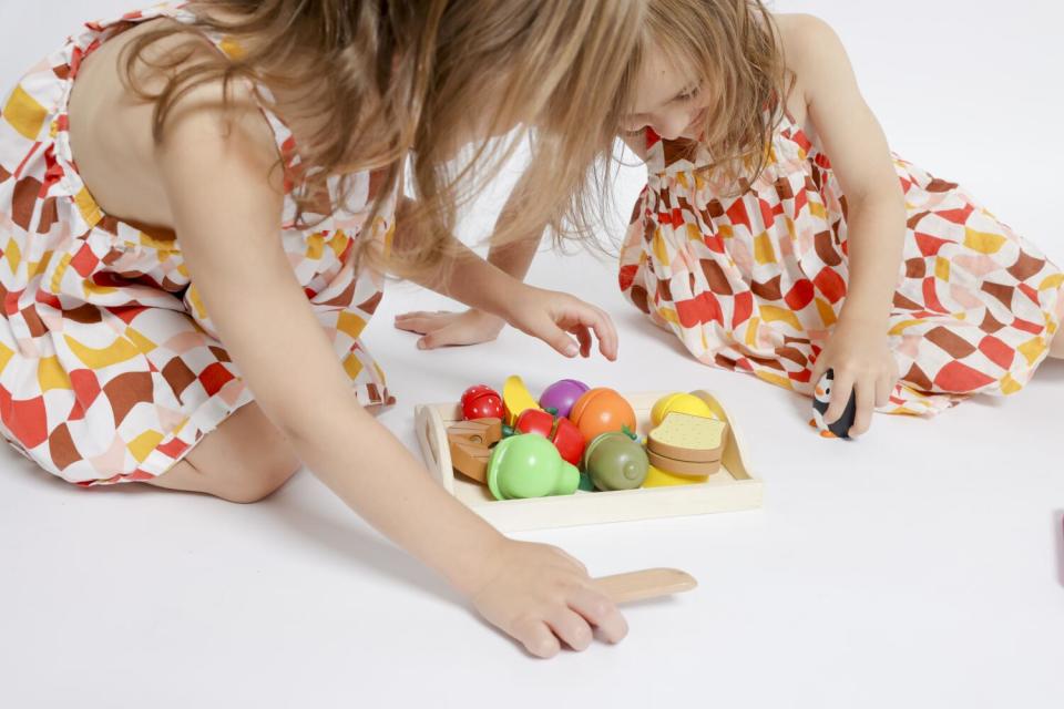 River and Penny Atchison, left and right, play with wooden and plastic toys at their home.