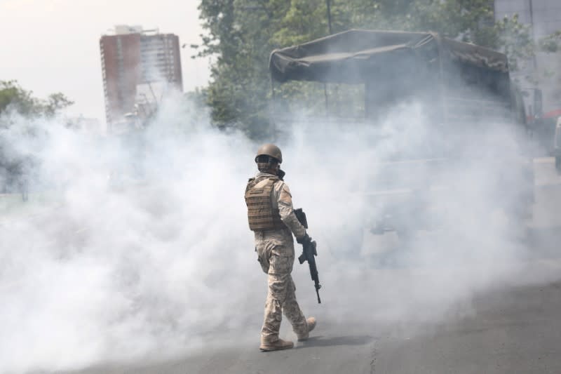 A soldier walks between tear gas during a protest against the increase in the subway ticket prices in Santiago