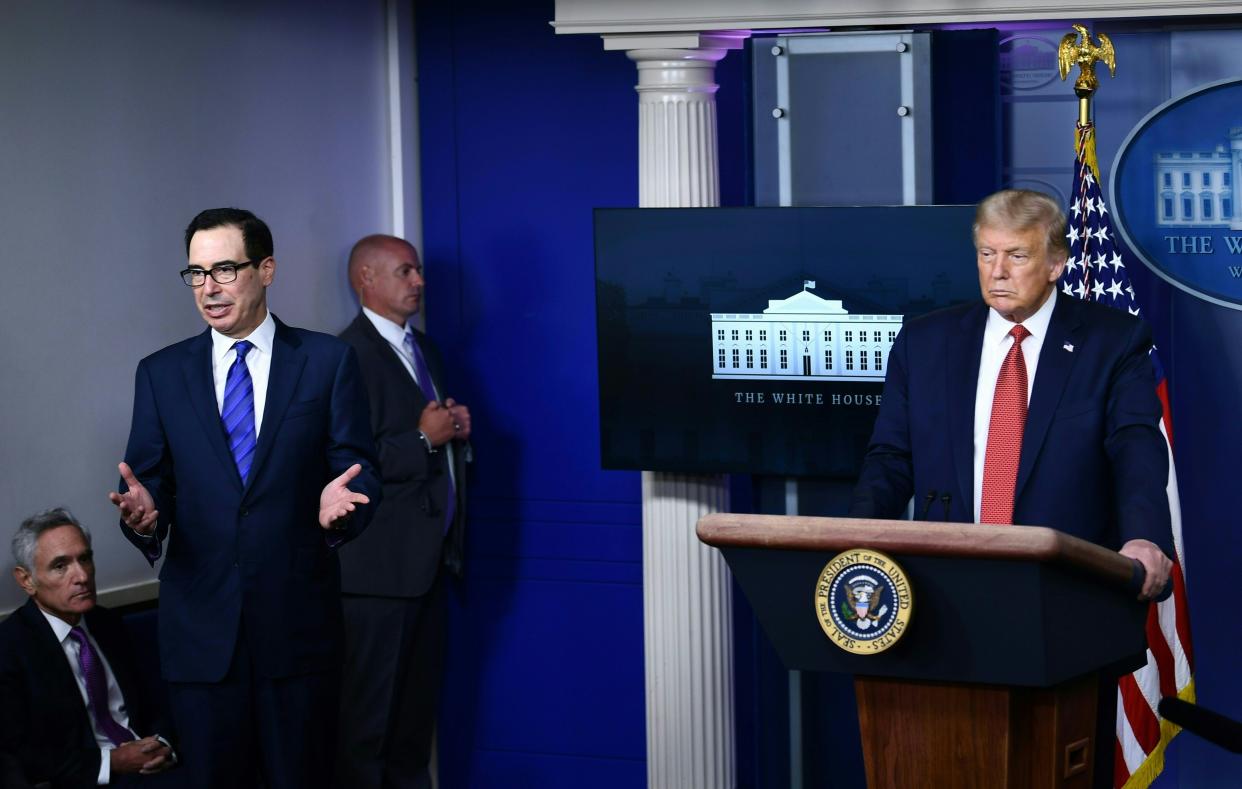 US President Donald Trump listens to Treasury Secretary Steven Mnuchin in the Brady Briefing Room of the White House in Washington, DC, on August 10, 2020. - Secret Service guards shot a person, who was apparently armed, outside the White House on Monday, President Donald Trump said just after being briefly evacuated in the middle of a press conference. The president was abruptly ushered out of the press event and black-clad secret service agents with automatic rifles rushed across the lawn north of the White House. Minutes later, Trump reappeared at the press conference, where journalists had been locked in, and announced that someone had been shot outside the White House grounds. Trump said he knew nothing about the identity or motives of the person shot, but when asked if the person had been armed, answered: "From what I understand, the answer is yes." (Photo by Brendan Smialowski / AFP) (Photo by BRENDAN SMIALOWSKI/AFP via Getty Images)