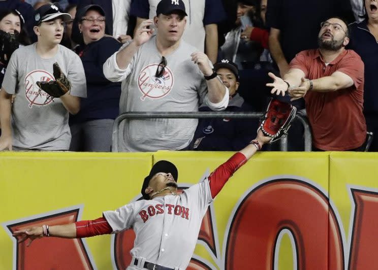 Red Sox right fielder Mookie Betts battles a fan for Chris Carter's fly ball. (AP)