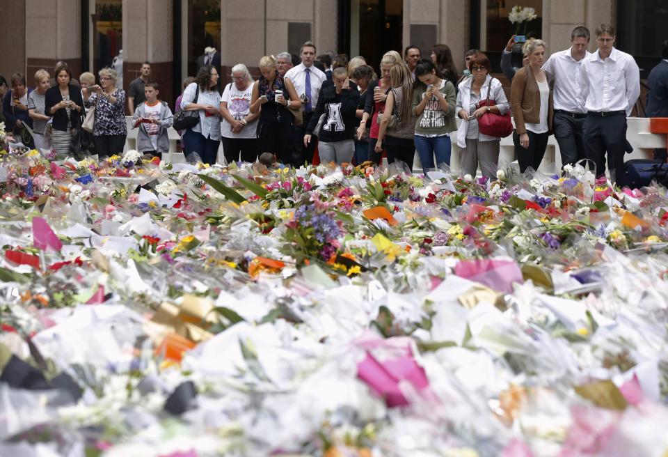 Three unidentified relatives (3rd R-R) of Sydney cafe siege victim, lawyer Katrina Dawson, gather after laying a floral tribute to her in Martin Place December 18, 2014. REUTERS/Jason Reed 