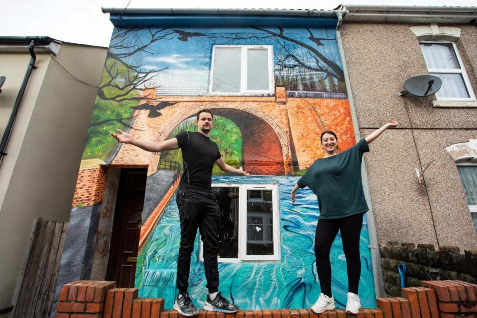 'Canal house' couple Nick and Megan Underwood posing proudly in front of their newly painted home <i>(Image: SWNS)</i>