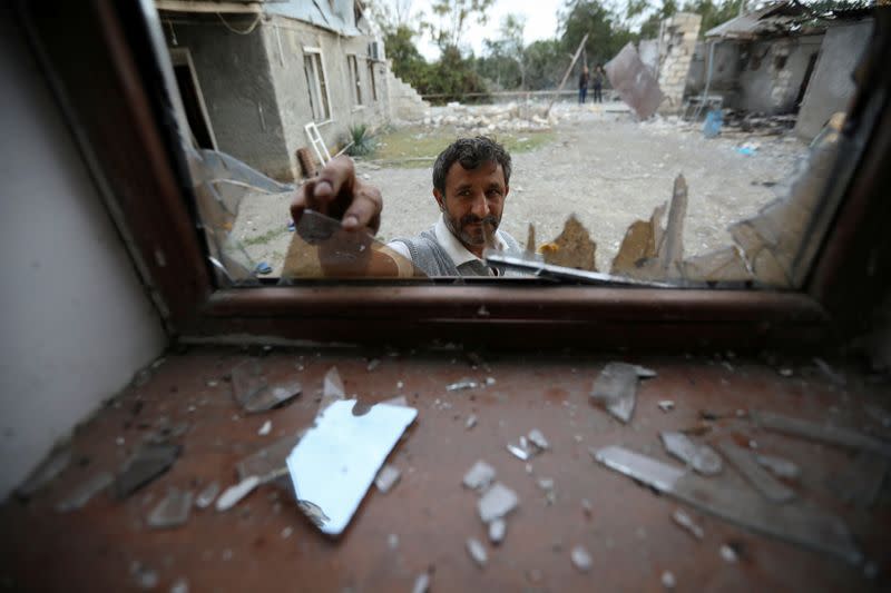 A man removes broken glass in a window damaged after shelling in the fighting over the breakaway region of Nagorno-Karabakh in the village of Garagoyunlu