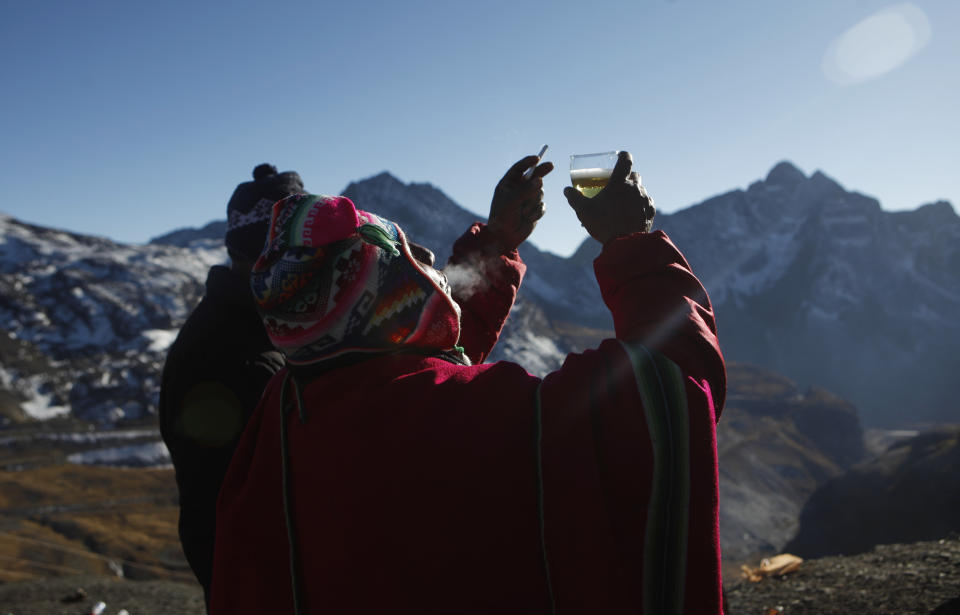An Aymara priest raises his glass of beer and blows out cigarette smoke at the end of an offering ceremony to "Pachamama," or "Mother Earth," on La Cumbre, a mountain that is considered scared ground, on the outskirts of La Paz, Bolivia, Friday, Aug. 1, 2014. The month of August is the time people gather in the mountains of Bolivia to make offerings in honor of the earth goddess and ask for good fortune. According to local agrarian tradition, Mother Earth awakes hungry and thirsty in August and needs offerings of food and drink in order for to be fertile and yield abundant crops. (AP Photo/Juan Karita)