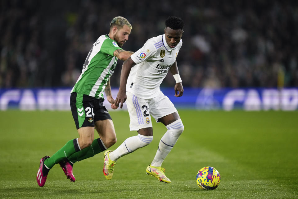 Betis' Aitor Ruibal, left, challenges Real Madrid's Vinicius Junior during the Spanish La Liga soccer match between Real Betis and Real Madrid at the Benito Villamarin stadium in Seville, Spain, Sunday, March 5, 2023. (AP Photo/Jose Breton)