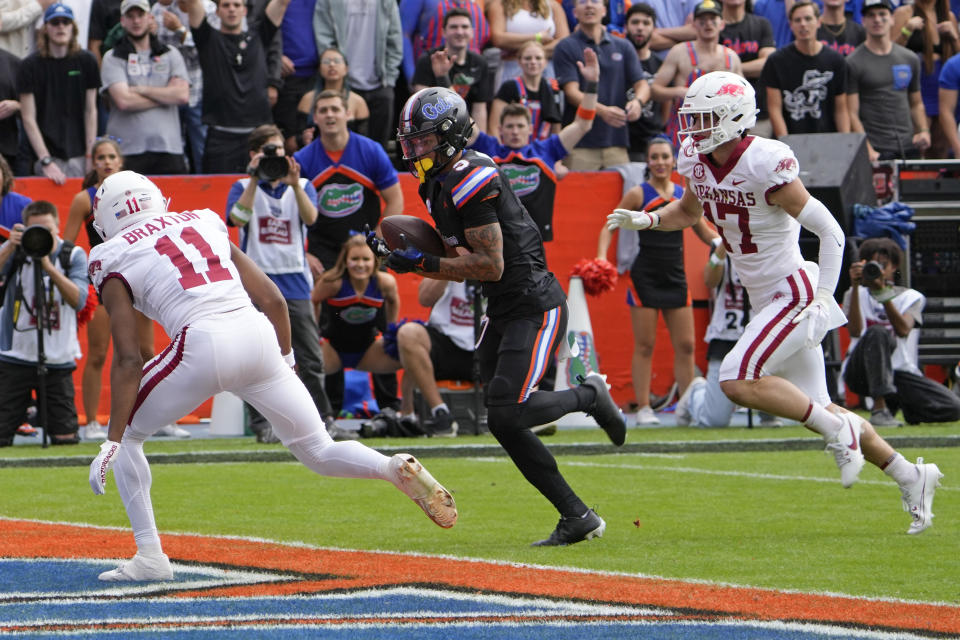 Florida wide receiver Eugene Wilson III, center, gets past Arkansas defensive back Jaylon Braxton (11) and defensive back Hudson Clark (17) for a 19-yard touchdown on a pass play during the first half of an NCAA college football game, Saturday, Nov. 4, 2023, in Gainesville, Fla. (AP Photo/John Raoux)