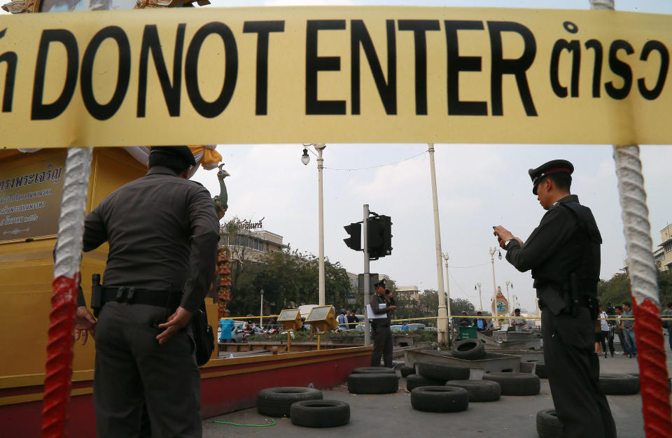 Thai police officers examine the site where a bomb exploded Monday, Feb. 10, 2014 in Bangkok, Thailand. Six street cleaners have been wounded by a small explosion at an anti-government protest site in Thailand's capital on Monday, police said. (AP Photo)