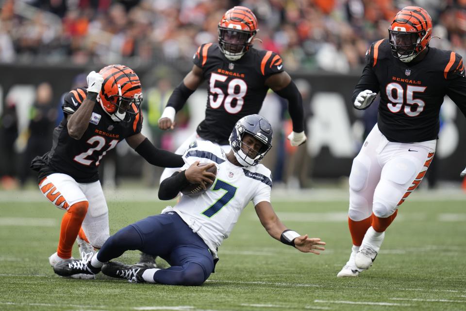 Seattle Seahawks quarterback Geno Smith slides in front of Cincinnati Bengals' Mike Hilton (21) during the second half of an NFL football game, Sunday, Oct. 15, 2023, in Cincinnati. (AP Photo/Michael Conroy)