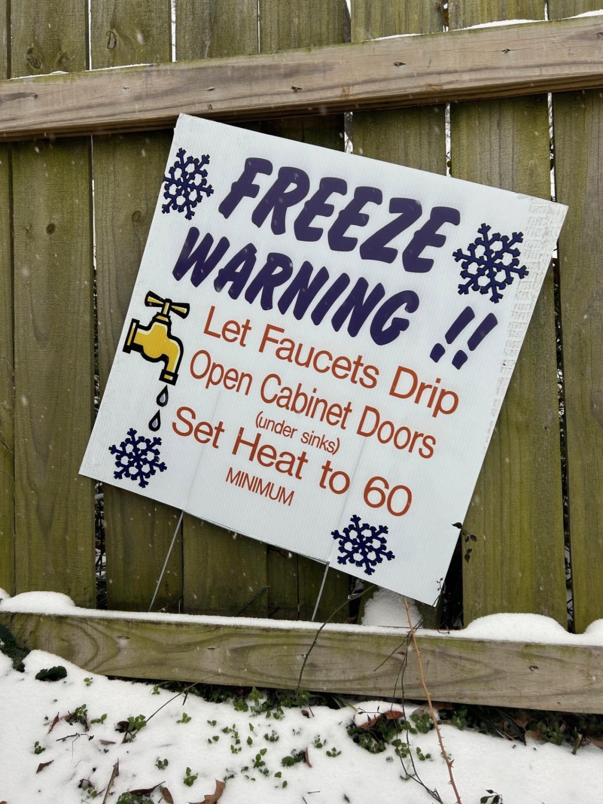 A sign warning about winter weather is seen along a snowy fence in Midtown Memphis on Sunday, Jan. 14, 2024. The Memphis area is expecting 3 to 6 inches of snow and below-freezing temperatures.