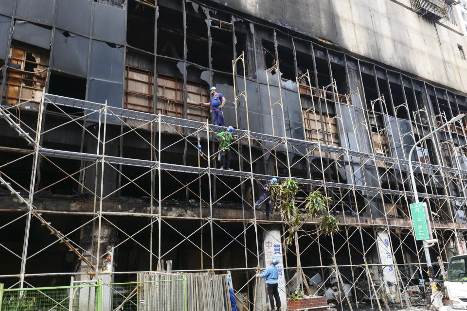 Workers setup scaffolding around the charred building after a major fire in Kaohsiung, southern Taiwan, Friday, Oct. 15, 2021. Taiwanese officials set up an independent commission Friday to investigate the conditions at a run-down building in the port city of Kaohsiung where a fire killed over forty people, while authorities scoured the blackened ruins for the cause of the blaze. (AP Photo/Huizhong Wu)