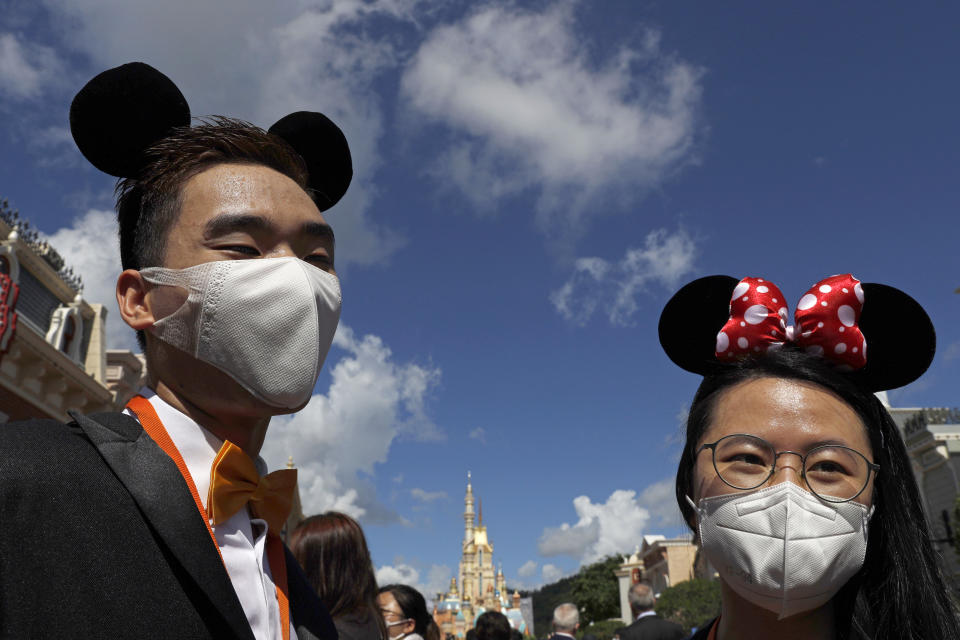 Visitors wearing face masks to prevent the spread of the new coronavirus, attend a reopening ceremony at the Hong Kong Disneyland on Thursday, June 18, 2020. Hong Kong Disneyland on Thursday opened its doors to visitors for the first time in nearly five months, at a reduced capacity and with social distancing measures in place. The theme park closed temporarily at the end of January due to the coronavirus outbreak, and is the second Disney-themed park to re-open worldwide, after Shanghai Disneyland. (AP Photo/Kin Cheung)