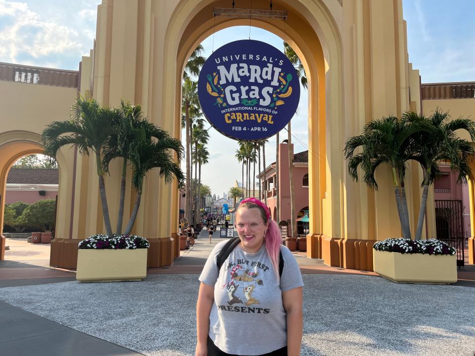 casey posing in front of mardi gras poster hanging on entrance to universal theme park