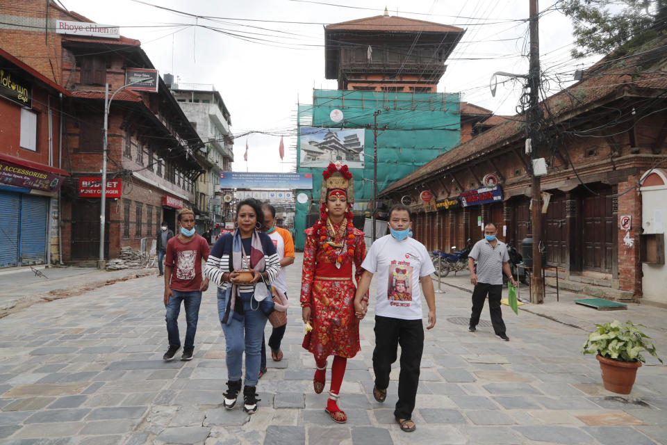 Living God Ganesh, center, walks back home after a ritual was performed during Indrajatra festival as the festival was canceled to control the spread of the coronavirus in Kathmandu, Nepal, Sunday, Aug. 30, 2020. A lockdown was ordered around the eight days when the canceled Indrajatra festival would have been held, and instead, a small ceremony to seek forgiveness from Indra, the Hindu god of rain, was held under government security. Many in this Himalayan nation believe they would anger the gods by shunning the rituals — which would cause catastrophe. (AP Photo/Niranjan Shrestha)