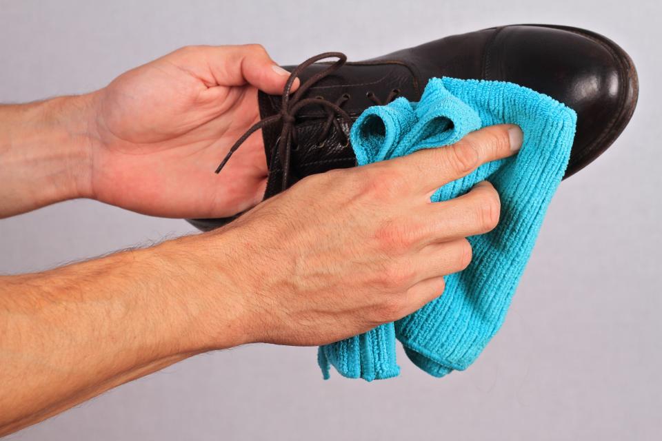 Leather shoes winter care. Man cleaning shoes close up