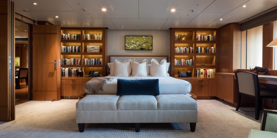 A bedroom with a large bed, desk, bookshelves.