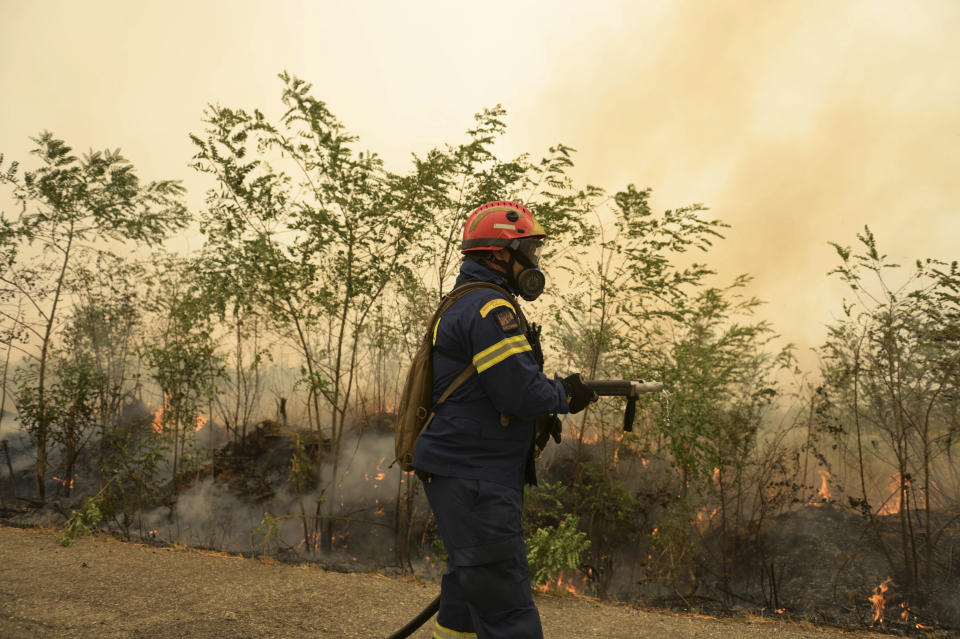 A firefighter waits to spray water as flames burn a forest during a wildfire in Giannouli village, in the northeastern Evros region, Greece, Thursday, Aug. 31, 2023. Greek authorities have further reinforced firefighting forces in the country's northeast, where a massive blaze in its thirteenth day has flared up once more, triggering authorities to issue alerts to residents in the area to be on standby for possible evacuation. (e-evros.gr via AP)