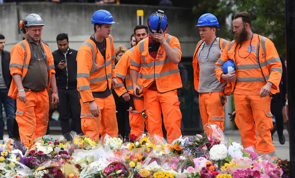 A group of construction workers react as they leave flowers on the south side of London Bridge