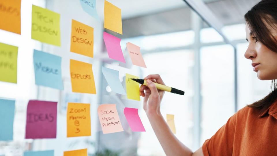 Mujer escribiendo en papeletas autoadhesivas o post its.