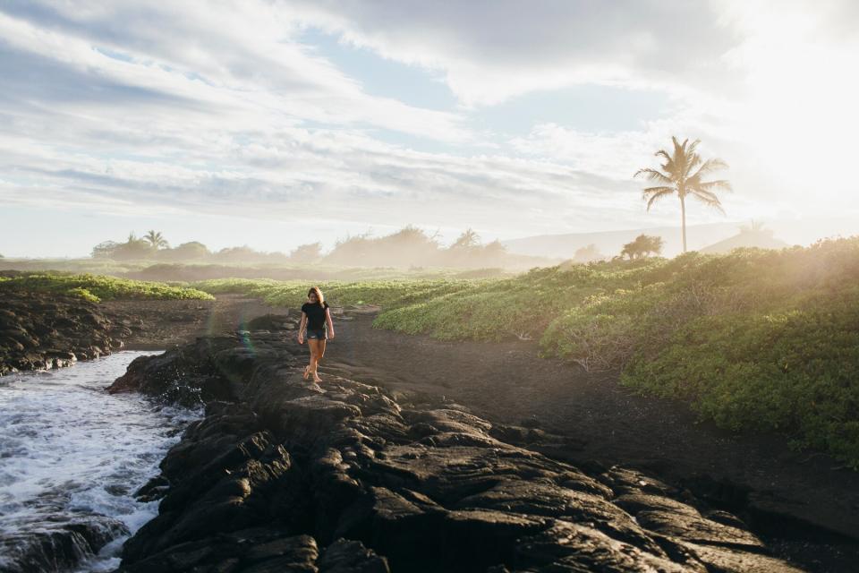 A person is walking on lava rocks near the ocean, Big Island, Hawaii.