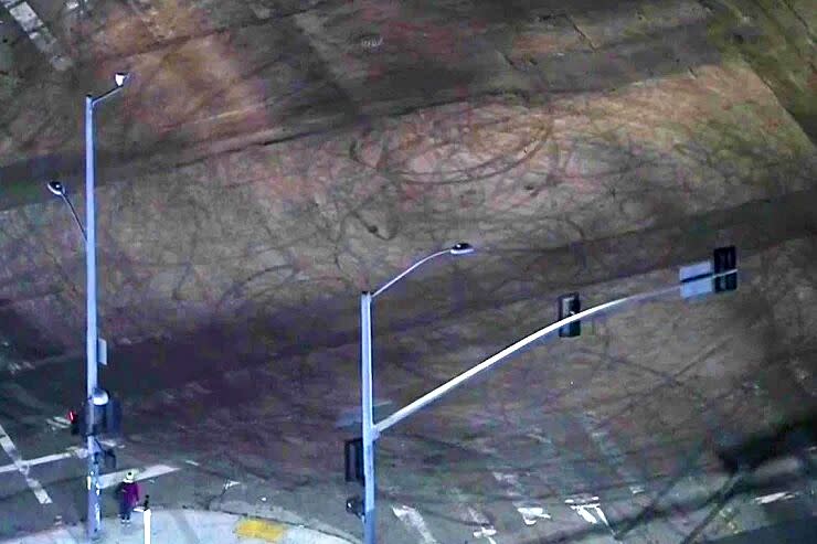 An aerial view of a stop-light intersection with pavement marked by dark large circles by tires.