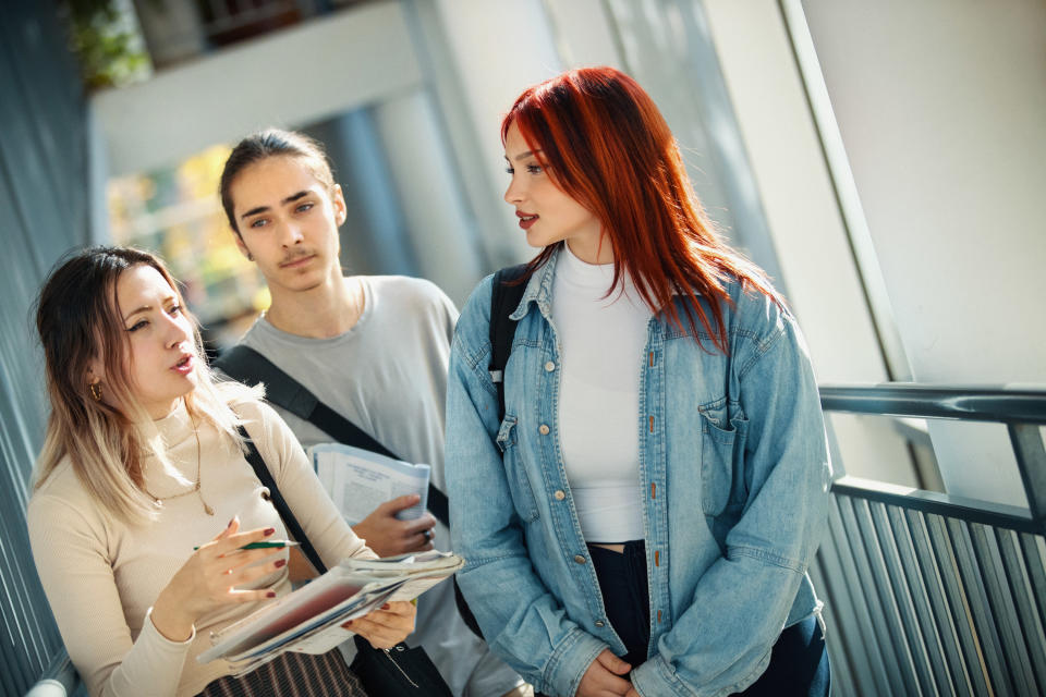 three teenagers talking in the hallway at school