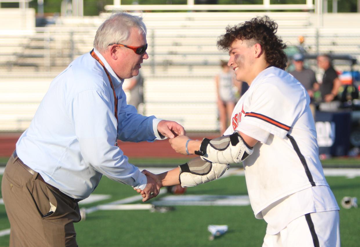 Brighton's Ryan Velarde receives his regional championship medal from Brighton athletic director John Thompson following an 8-6 victory over South Lyon Wednesday, May 31, 2023 at South Lyon East.