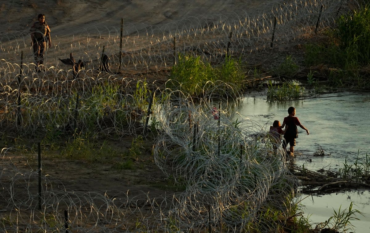 Migrants walk along concertina wire as they try to cross the Rio Grande at the Texas-U.S. border in Eagle Pass, Texas, Thursday, July 6, 2023 (Copyright 2023 The Associated Press. All rights reserved)
