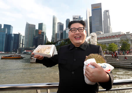 Howard, an Australian-Chinese impersonating North Korean leader Kim Jong Un, poses with a durian and a box of chicken rice at the Merlion Park in Singapore May 27, 2018. REUTERS/Edgar Su