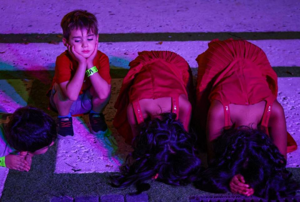 Kianah (al centro), de seis años, y su hermana, Alaia Ahmed (a la derecha), de 8, inclinándose en oración mientras un niño se sienta apasionadamente para el comienzo del festival. La comunidad india del sur de la Florida celebró el domingo el festival de las luces en Miami.