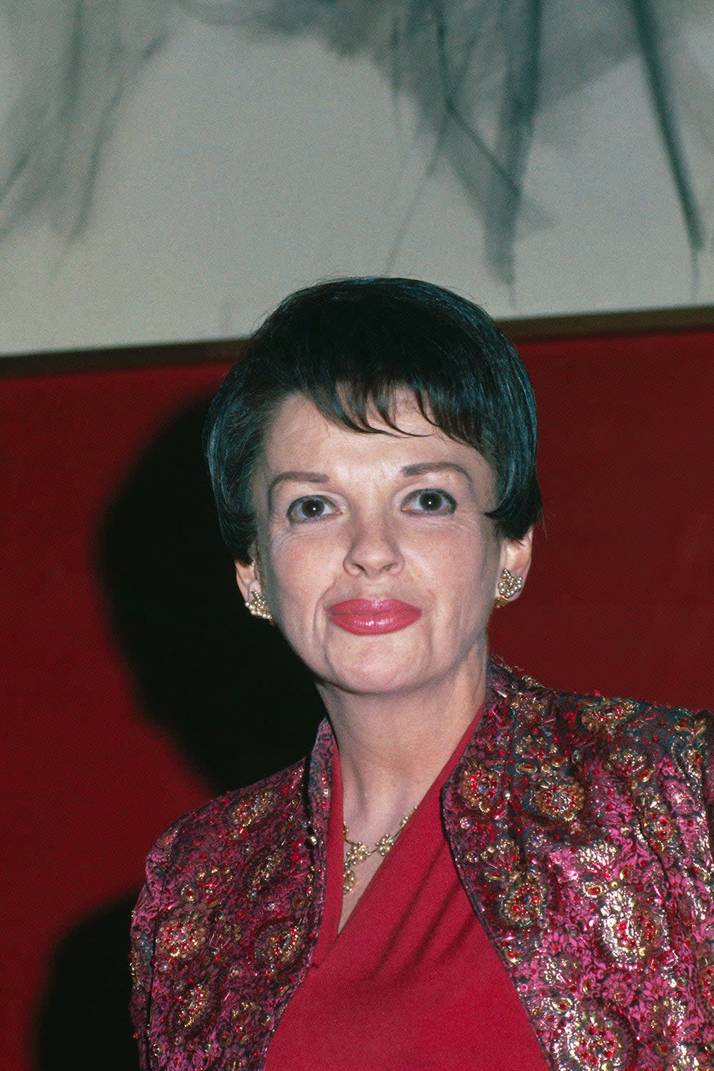 Judy Garland wearing a red blouse and a multicolored cardigan