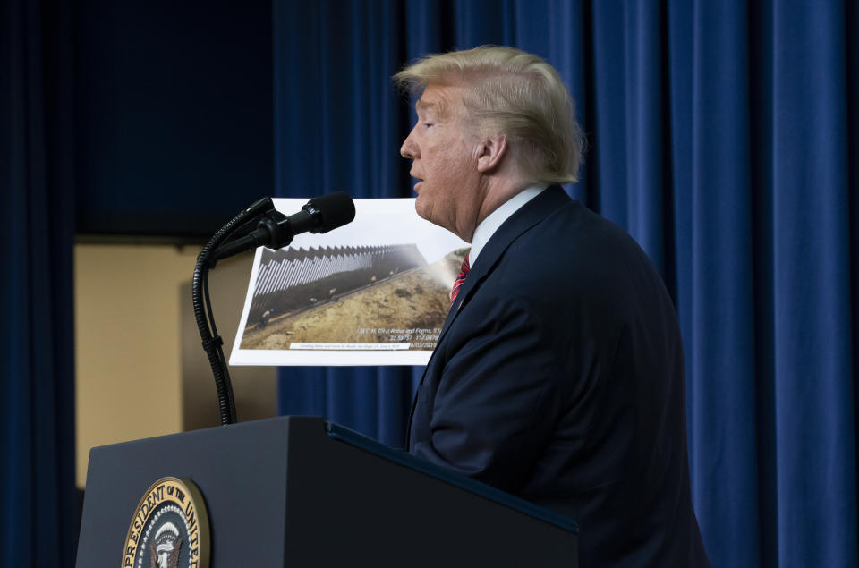 President Donald Trump displays photos of the border wall under construction as he speaks to members of the National Border Patrol Council at the White House in Washington, Friday, Feb. 14, 2020. (AP Photo/J. Scott Applewhite)