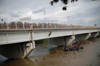 A Honduran migrant, part of a caravan trying to reach the U.S., climbs down from the bridge that connects Mexico and Guatemala with the help of fellow immigrants to avoid the border checkpoint in Ciudad Hidalgo, Mexico October 19, 2018. REUTERS/Ueslei Marcelino