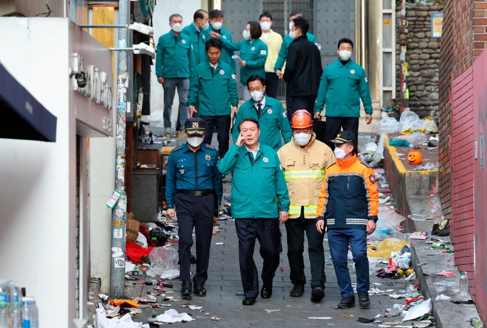 South Korean President Yoon Suk Yeol, center left, visits the scene where dozens of people died and were injured in Seoul, South Korea, Sunday, Oct. 30, 2022, after a mass of mostly young people celebrating Halloween festivities became trapped and crushed as the crowd surged into a narrow alley.