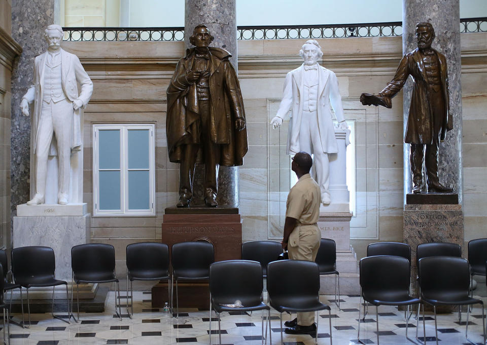 US Navy Lt. William Edmund Newsome looks at a bronze statue of Confederate president Jefferson Davis (2ndL) that stands inside of Statuary Hall at the US Capitol June 24, 2015 in Washington, DC. (Photo by Mark Wilson/Getty Images)