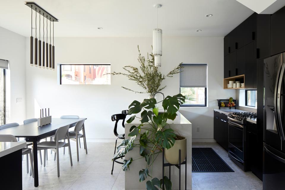 In the dining room, the Soft Edge 12 side chairs designed by Iskos-Berlin for HAY and the Muuto adaptable table are all from DWR. The lighting fixture is by CB2. In the open kitchen, the black French T-back stools from RH contrast with the recycled tube-light pendant by Castor design.