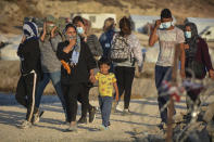 Migrants are seen inside the new temporary refugee camp in Kara Tepe, on the northeastern island of Lesbos, Greece, Saturday, Sept. 19, 2020. Police on the Greek island of Lesbos on Friday resumed relocating migrants rendered homeless when fires ravaged the country's largest refugee camp amid a local COVID-19 outbreak. (AP Photo/Panagiotis Balaskas)