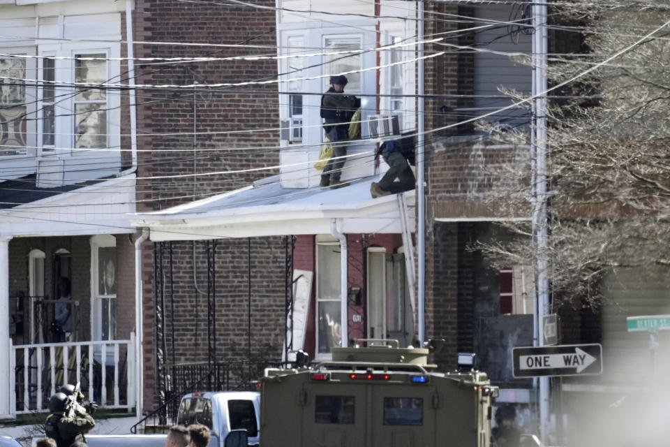 FILE - Police surround a home in Trenton, N.J., Saturday, March 16, 2024. A suspect has barricaded himself in the home and was holding hostages after shooting three people to death in suburban Philadelphia. Andre Gordon Jr., charged with fatally shooting three relatives in Pennsylvania, carjacking another person, as well as evading police for hours in New Jersey, is set to appear in a New Jersey court on gun charges. (AP Photo/Matt Rourke, File)