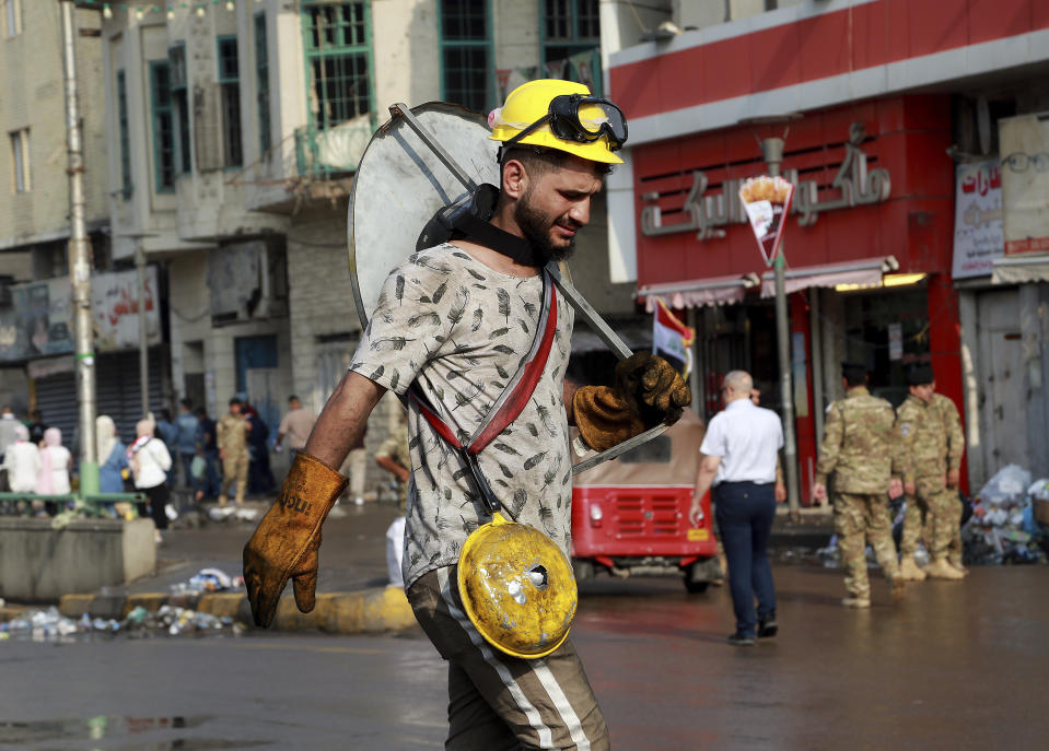 An anti-government protester uses a piece of tin as a shield during a demonstration in Tahrir Square, Baghdad, Iraq, Wednesday, Oct. 30, 2019. Anti-government protests in Iraq gained momentum Wednesday with tens of thousands of people gathered in a central square in Baghdad and across much of the country's Shiite-majority central southern provinces. (AP Photo/Hadi Mizban)