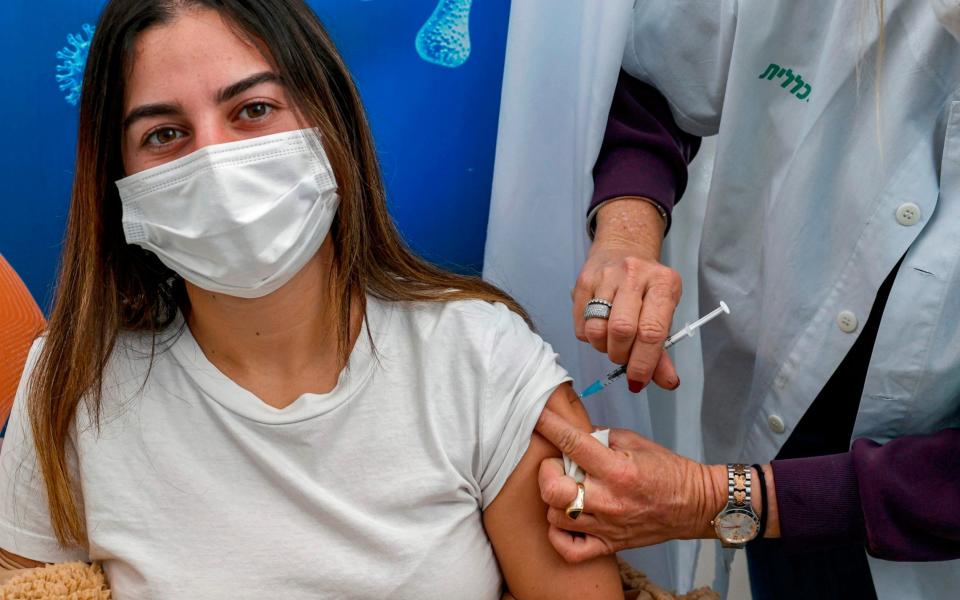 An 18-year-old teenager, receives a dose of the Pfizer-BioNtech Covid-19 coronavirus vaccine at Clalit Health Services, in Israel's Mediterranean coastal city of Tel Aviv - JACK GUEZ /AFP 